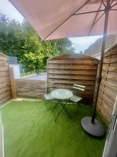 un patio avec une table et un parasol dans l'établissement dday cottage gold beach, à Saint-Côme-de-Fresné