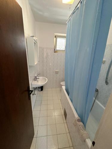 a bathroom with a shower curtain and a sink at Apartments and rooms Velada in Hvar