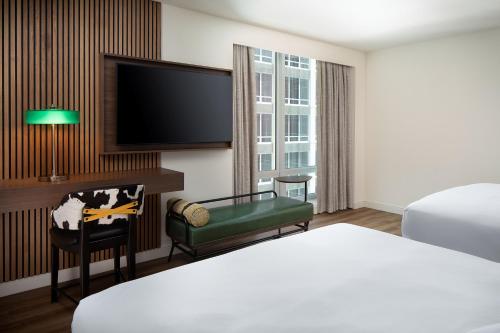 a hotel room with a bed and a flat screen tv at Le Meridien Fort Worth Downtown in Fort Worth