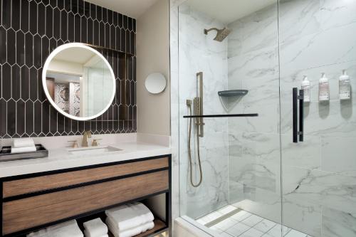 a bathroom with a shower and a sink and a mirror at Le Meridien Fort Worth Downtown in Fort Worth