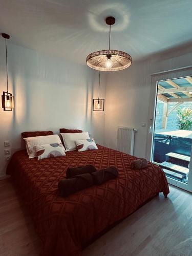 une chambre avec un grand lit avec une couverture rouge dans l'établissement Pura Vida Spa - gîte avec spa extérieur couvert, à Écaillon