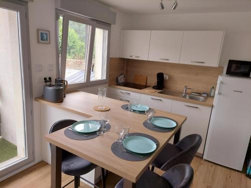 d'une cuisine avec une table en bois et 4 assiettes. dans l'établissement Traezh - appart-sympa - T3 en plein centre de Plœmeur, à Ploemeur