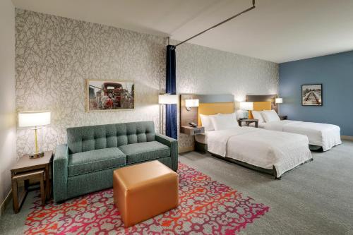 a hotel room with two beds and a couch at Home2 Suites By Hilton Sanford in Sanford