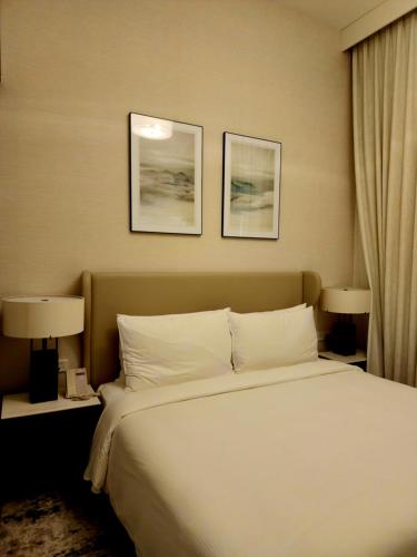a bed in a hotel room with two pictures on the wall at Apartment at Address Beach Resort Sharm Al Aqah in Fujairah
