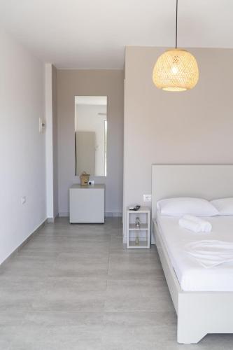 a white bedroom with a bed and a table at Koks’ Guesthouse in Himare