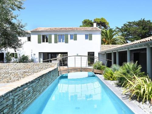 un pont sur une piscine en face d'une maison dans l'établissement Maison spacieuse avec piscine et accès plage - FR-1-434-69, aux Portes