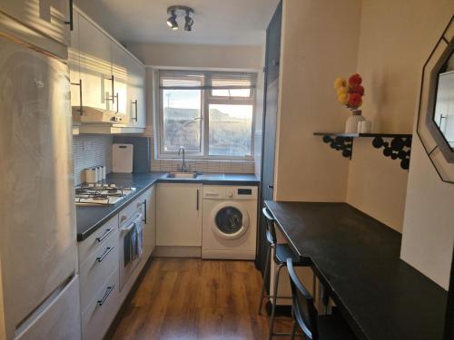 a kitchen with a sink and a washing machine at Elegant & Spacious 2-Bedroom Apartment in Wimbledon in London