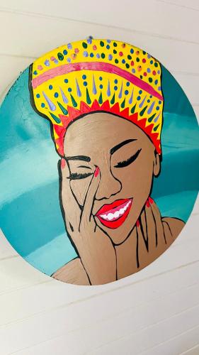 a painting of a woman wearing a colorful hat at Île tropical lodges in Sainte-Anne