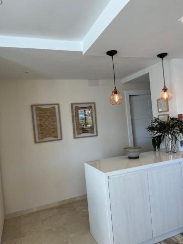 a white kitchen with two lights and a counter at Ático Solymar in Almuñécar