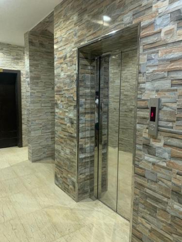a elevator in a lobby with a stone wall at رؤى القنفذة للشقق المخدومة in Al Qunfudhah