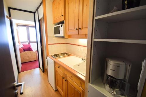 une petite cuisine avec un évier et un micro-ondes dans l'établissement Résidence Le France - Studio 2pers LE FRANCE PLAGNE CENTRE MAE-9594, à Aime La Plagne