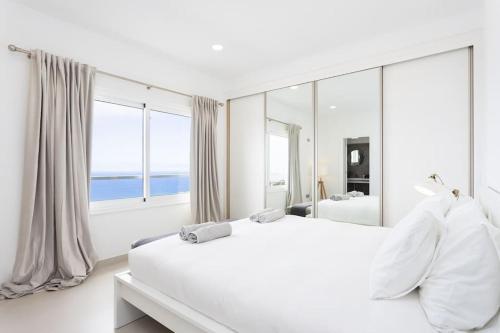 ein weißes Schlafzimmer mit einem großen Bett und einem großen Fenster in der Unterkunft Villa de lujo Concordia Piscina climatizada y excelentes vistas in Puerto de la Cruz