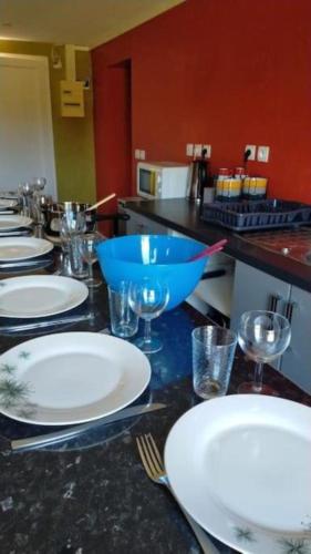 une table avec des assiettes, des bols et des verres dessus dans l'établissement Kindia au Mans Maison 7pers, 3km circuit des 24H, à Arnage