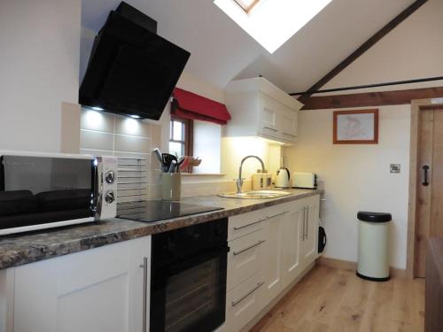 The Granary Thirsk Luxury Holiday Cottage Barn في ثيرسك: مطبخ مع ميكروويف وطاولة عمل