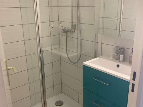 La salle de bains est pourvue d'une douche, d'une armoire bleue et d'un lavabo. dans l'établissement Villa Face au Lac avec Terrasse et Barbecue - 3 Pièces + Mezzanine pour 6 Personnes - FR-1-81-96, à Port-Leucate
