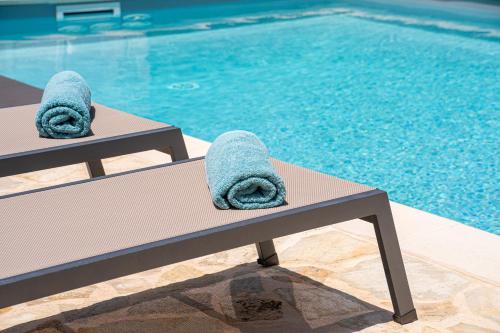 a pair of towels sitting on a bench next to a swimming pool at Blue Villa in Sami