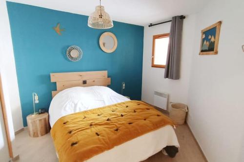 une chambre avec un lit et un mur bleu dans l'établissement Les 3 Flocons, Meublé classé 3 étoiles , labellisé 4 grif, à Orcières