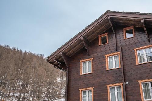 a wooden house with windows and trees in the background at Chalet Edelweiss in Saas-Almagell