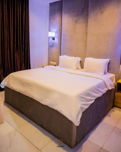 a large bed with white sheets and pillows at Lavani Apartment in Benin City