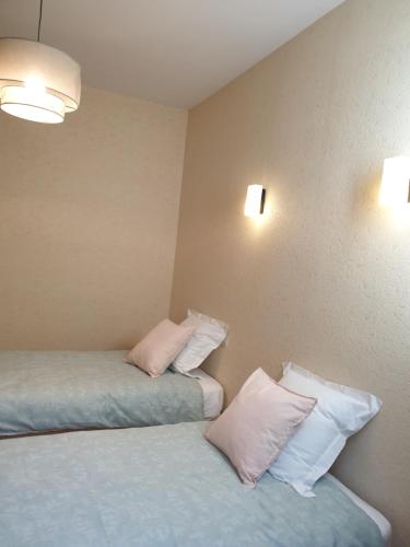 two beds in a room with pink and white pillows at Aux gorges du Dourdou in Conques-en-Rouergue