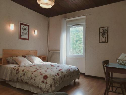 a bedroom with a bed and a window and a desk at Aux gorges du Dourdou in Conques-en-Rouergue