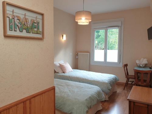 a room with two beds and a table and a window at Aux gorges du Dourdou in Conques-en-Rouergue