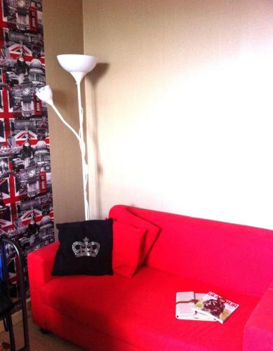- un canapé rouge dans le salon avec une lampe dans l'établissement Room confortable next to the Olympic venues, à Villeneuve-la-Garenne