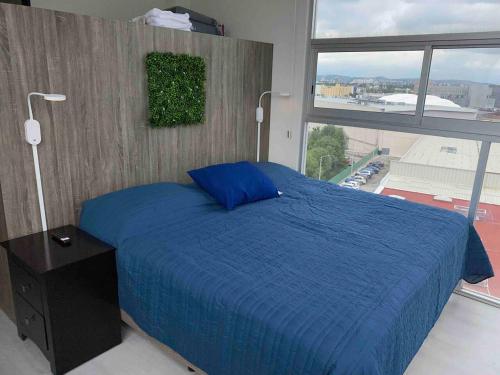 ein Schlafzimmer mit einem blauen Bett und einem großen Fenster in der Unterkunft NUEVO Penthouse para 8 en la Estrella de Puebla in El Gallinero