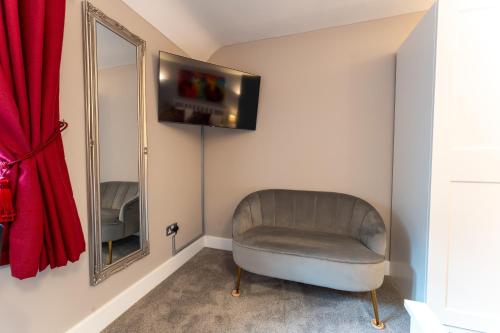 a chair in a room with a mirror and a red curtain at Luxury En-Suite Room 2 in Blewbury Oxfordshire in Blewbury