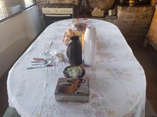 a table with a white table cloth with a jug and cups at Chales rota da pedra in São Bento do Sapucaí