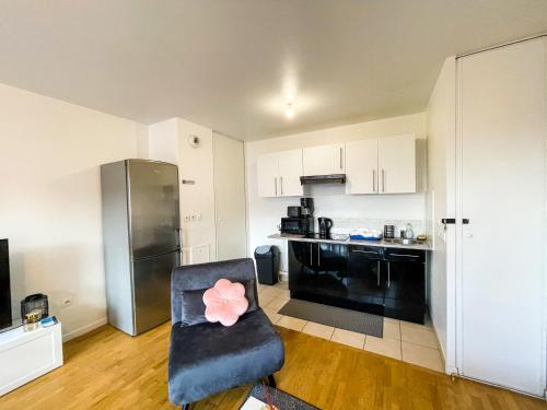 un salon avec une chaise et une cuisine dans l'établissement Appartement à 5 min de Disneyland Paris idéal pour familles et couples, à Bussy-Saint-Georges
