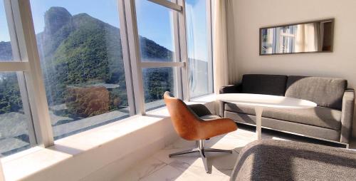 a living room with a couch and a chair and large windows at Hotel Nacional Rio de Janeiro - OFICIAL in Rio de Janeiro