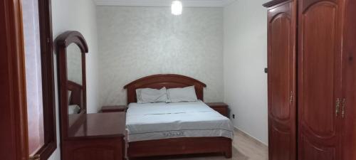 a bedroom with a bed with a wooden headboard and a mirror at Appartement vu plage kemado in Al Hoceïma