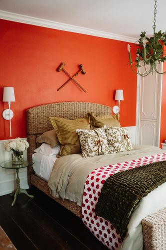 a bedroom with an orange wall and a bed with pillows at The Federal Inn in Maumee