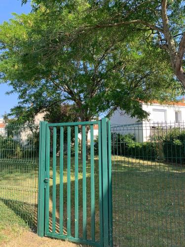 un portail vert devant une clôture avec un arbre dans l'établissement Studio Rochelais, à La Rochelle