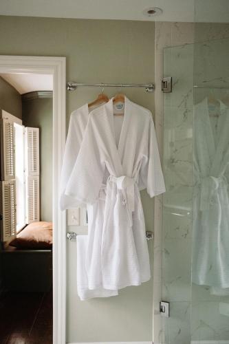 a white robe hanging on a door in a bathroom at The Federal Inn in Maumee