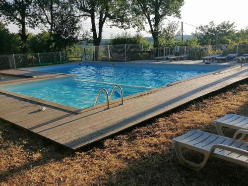 une grande piscine avec une terrasse en bois et des bancs dans l'établissement L'ESCALE de LARCHER 24250, à Saint-Aubin-de-Nabirat