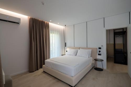 a bedroom with a white bed and a window at Arrei Hotel in Sarandë