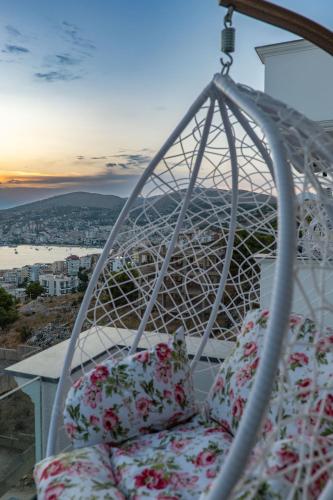 a white swing chair with flowers on a balcony at Arrei Hotel in Sarandë