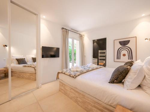 une chambre blanche avec un grand lit et un miroir dans l'établissement Villa Pinède proche plage et Saint Tropez, à Saint-Tropez