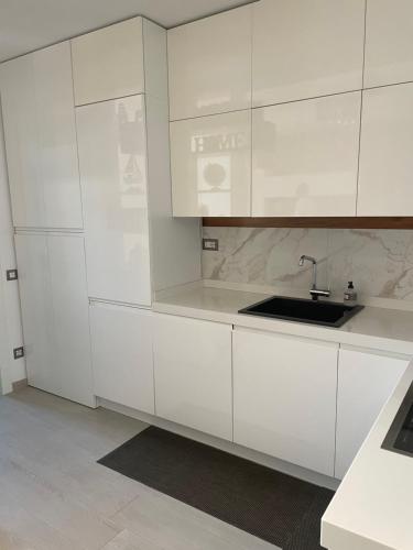 a white kitchen with white cabinets and a sink at Casa Regina in Civitanova Marche