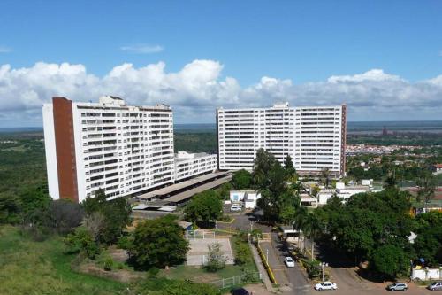 dos altos edificios blancos en una ciudad con coches en Apartamento de una habitacion con estacionamiento, en Santo Tomo