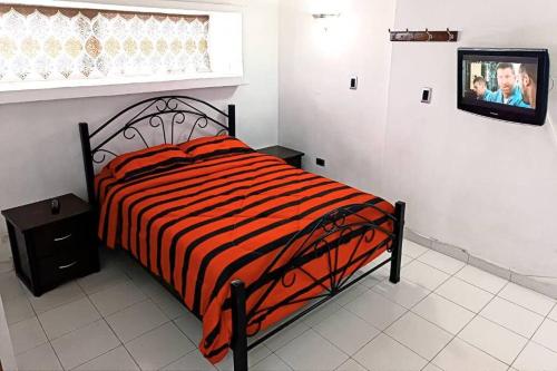 Un dormitorio con una cama y un televisor en una pared. en Apartamento de una habitacion con estacionamiento, en Santo Tomo