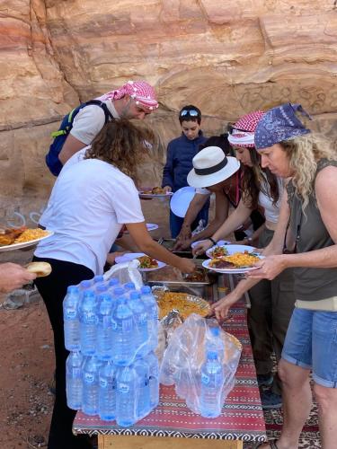 a group of people standing around a table with food at Rum relaxation luxury camp in Wadi Rum