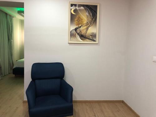 a blue chair in a room with a picture on a wall at Suite In City Center in Tirana
