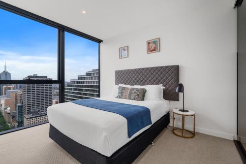 a bedroom with a bed and a large window at Collins House Apartments by CLLIX in Melbourne