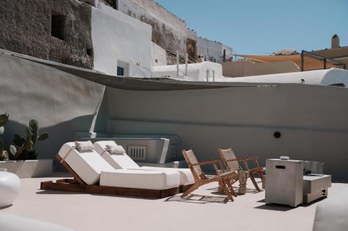 a patio with chairs and a table and a heater at Luna Santorini Suites in Pirgos