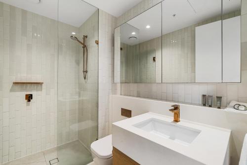 a white bathroom with a sink and a toilet at Collins House Apartments by CLLIX in Melbourne