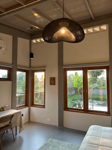 a bedroom with windows and a large light fixture at Liontree Villa in Kolongan