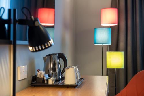 a table with a coffee maker and two lamps on it at Holiday Inn Edinburgh Zoo by IHG in Edinburgh